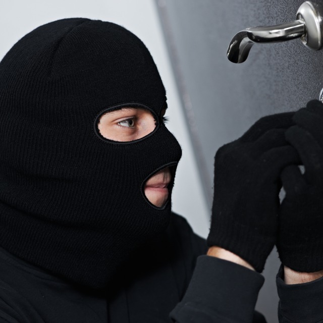 Thief Burglar force lock metal door with a tool during house breaking