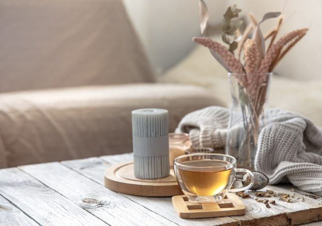 cozy-autumn-home-composition-with-cup-tea-candles-knitted-element-blurred-background-room-interior_169016-14056-640x450