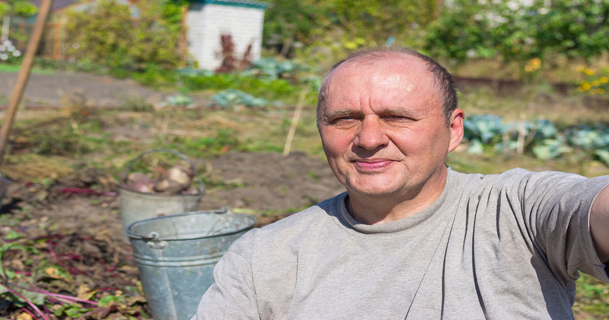 Portrait of a happy mature man making first selfie in his life against kitchen garden
