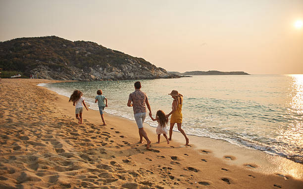 A family run hand in hand down a tropical paradise beach during sunset.